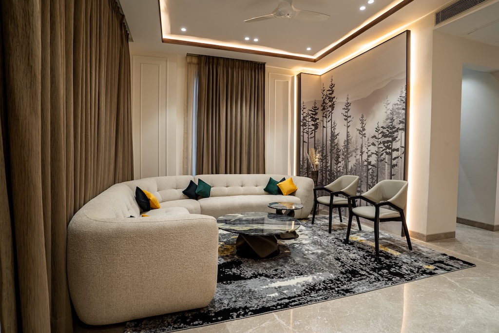 ZuildUp interior — living room with curved sectional, forest mural and cove ceiling